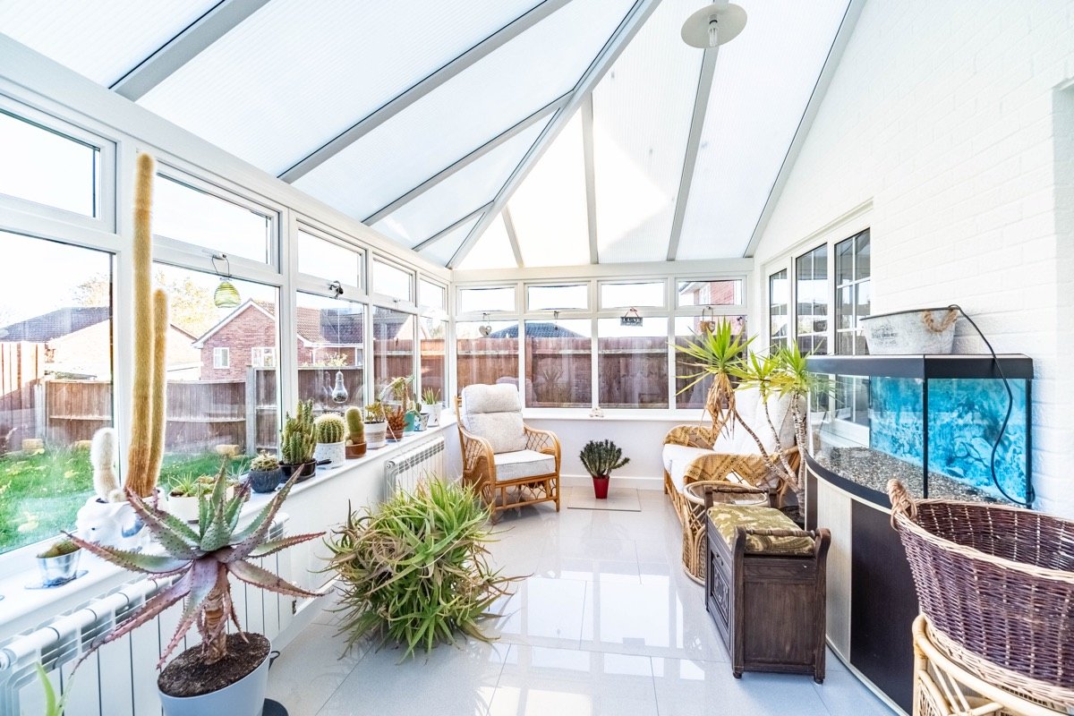 Bright conservatory with plants and wicker furniture