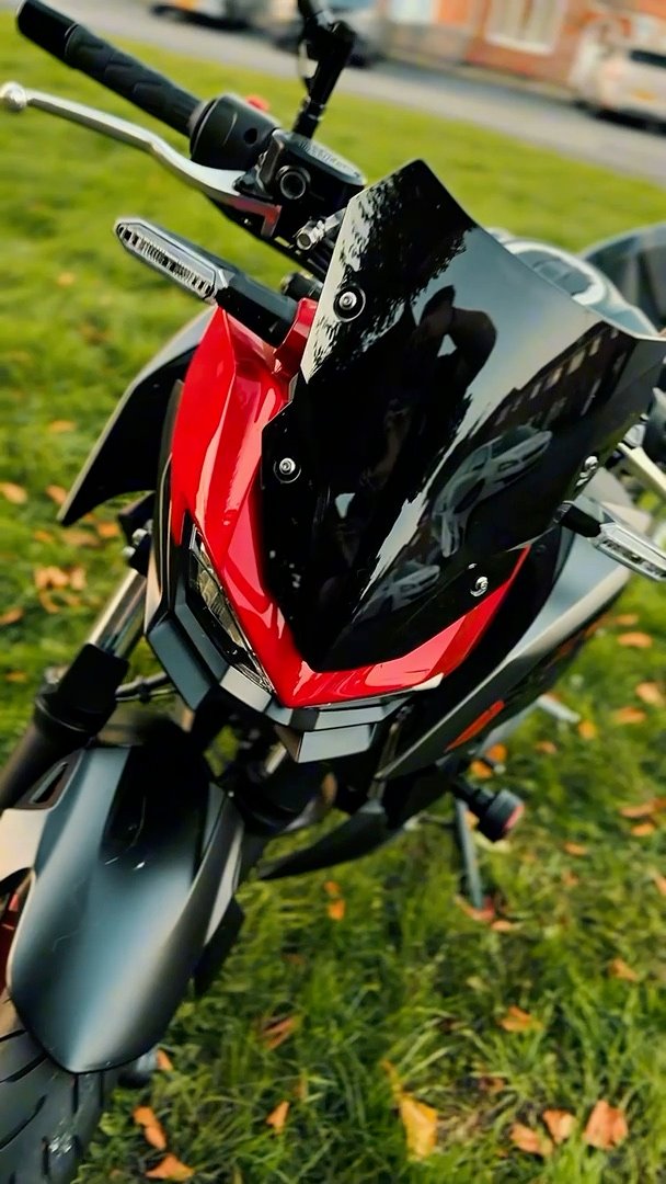 Still from a vertical reel of a red and black motorcycle parked on grass